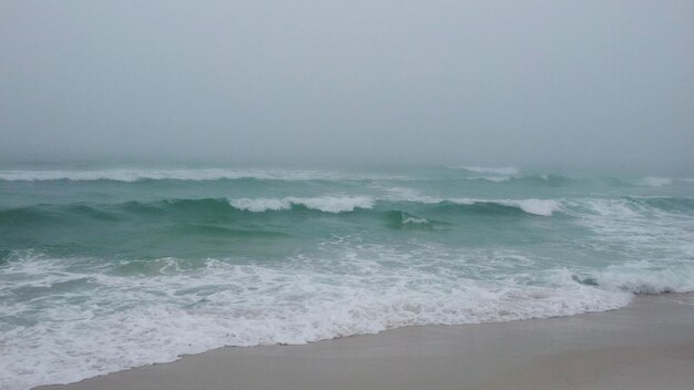 Waves rushing towards shore against clear sky