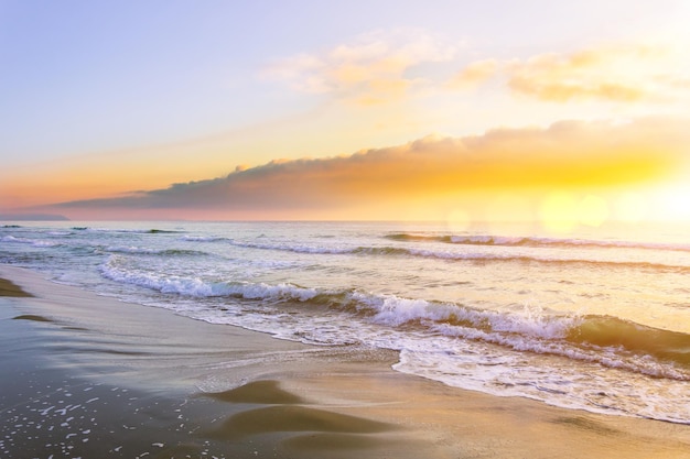 Waves on the sea before sunset, the sun shines in the clouds.