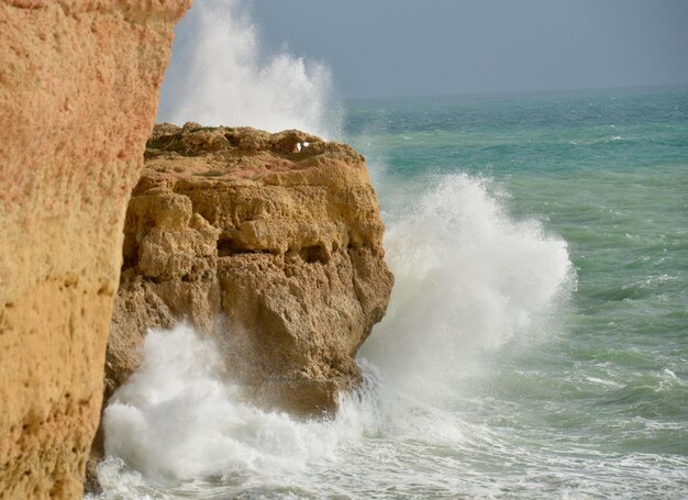 Foto le onde che schizzano sulla formazione rocciosa