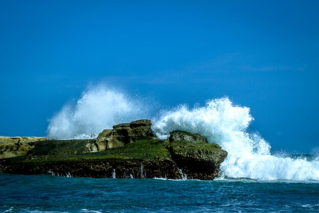 Waves splashing on rocks against blue sea