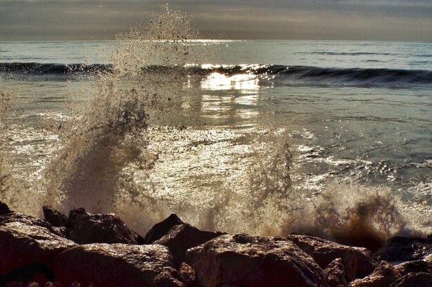 Foto le onde che schizzano le rocce in mare