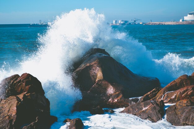 Foto le onde che schizzano sulle rocce sulla riva contro il cielo