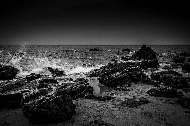 Foto le onde che schizzano sulle rocce sulla riva