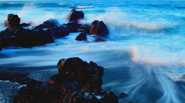 Photo waves splashing on rocks at shore