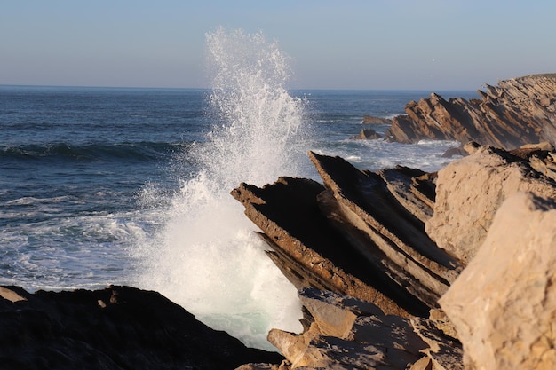 Foto le onde che schizzano sulle rocce sulla riva