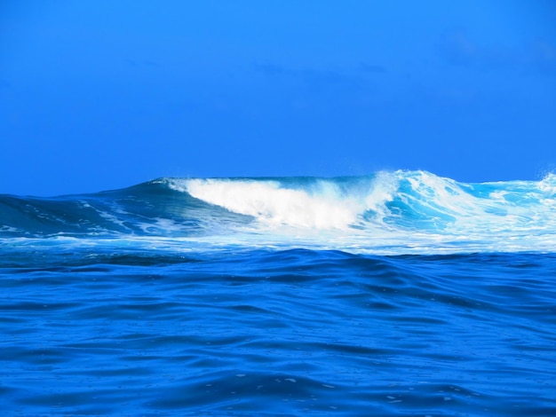 Foto le onde che schizzano sul mare contro il cielo blu limpido