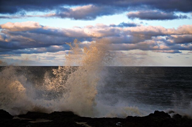 Foto le onde che schizzano sulla riva contro il cielo durante il tramonto