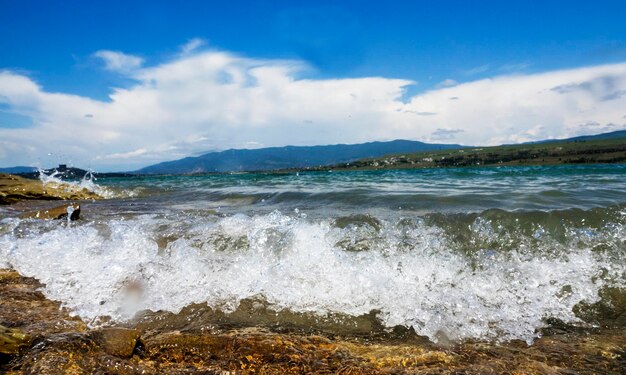 Waves splashing on shore against sky