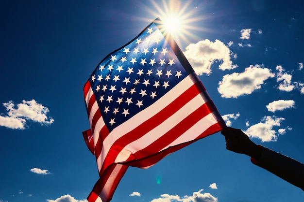 Waving american flag outdoors hand holds usa national flag against blue cloudy sky