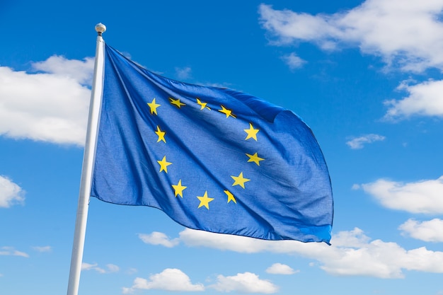 Waving European Union flag against blue sky background.