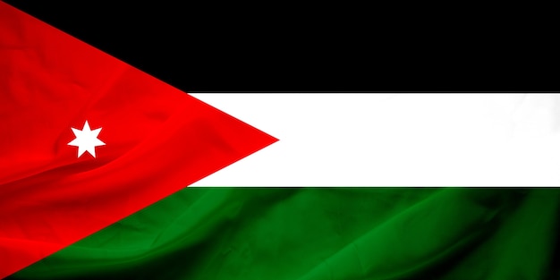 Foto sventolando la bandiera della giordania. la bandiera ha la trama del tessuto reale.