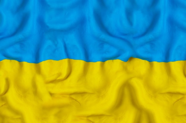 Waving flag of Ukraine made by hand with blue and yellow plasticine Pray for Ukraine