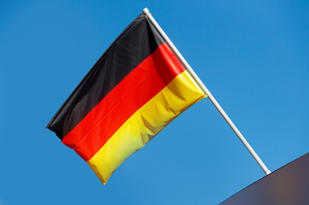 푸른 하늘에 대 한 기둥에 독일 국기를 흔들며