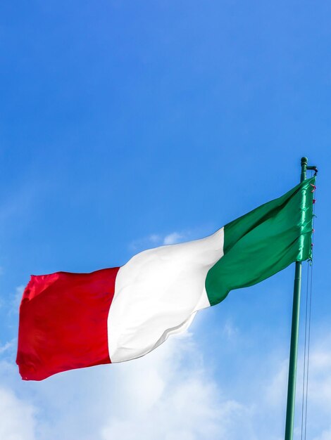 Waving Italian flag against blue sky