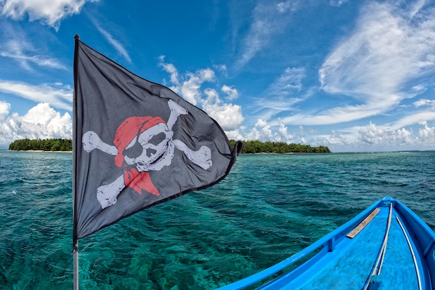 Waving pirate flag jolly roger on tropical island background