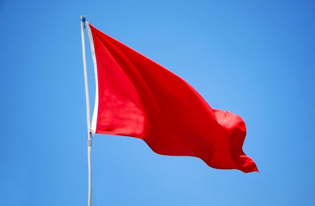 Waving red flag on blue sky background