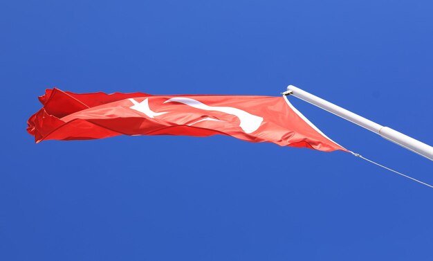 waving in the wind the Turkish Flag on a blue sky