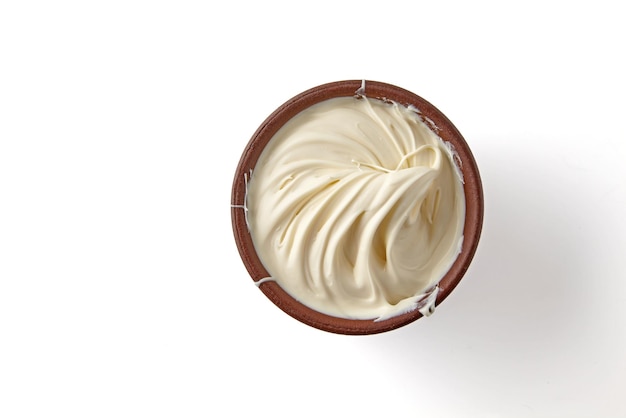 Wavy texture of yogurt cream in brown clay bowl isolated on white background Top view with copy space