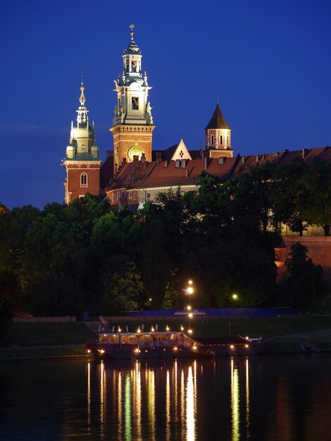 Photo wawel castle illuminated by night with reflections in vistula river