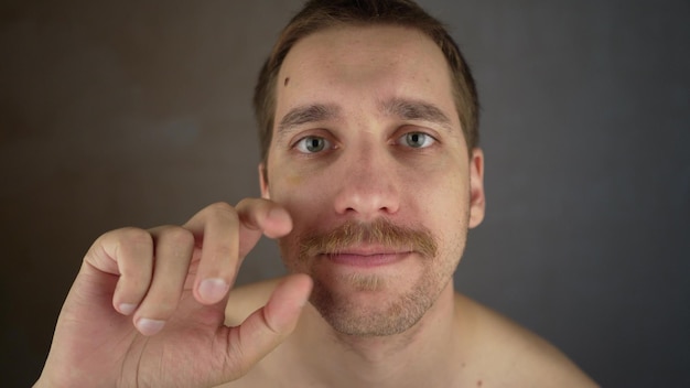 수염 관리용 왁스 남자가 콧수염을 왁싱합니다 남성 화장품 카메라를 보면서 콧수염을 정리합니다 셀프 케어 개념