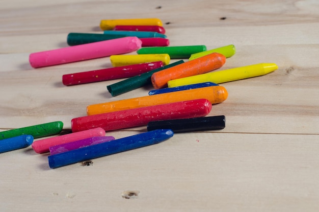 Wax crayons on white sheet wooden background