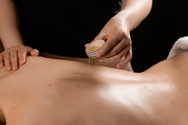 Waxing body massage with candle. Beauty spa procedure. Thai massage with warm wax.