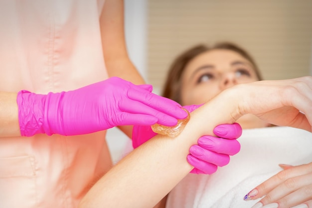 Waxing depilation hand and arm of the young woman lying in the spa salon