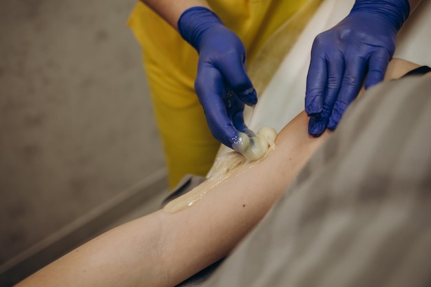 Waxing Depilation hand and arm of the young woman lying in the spa salon