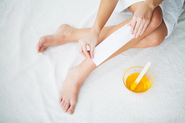 Waxing Young Woman Depilating Her Leg With Wax Stripe