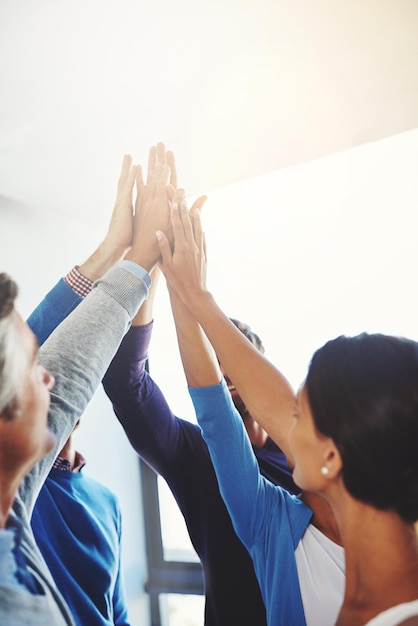 Photo way to go team shot of a group of businesspeople giving each other a high five