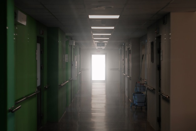 Wazig donkere ziekenhuisgang met een lichtgevende deur aan het einde een allegorie van klinische dood