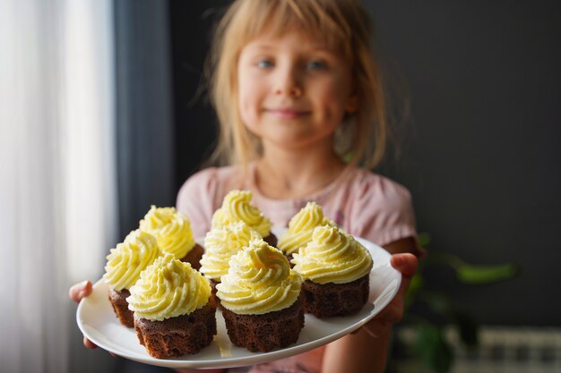 Wazig meisje met cupcakes op een bord in focus zelfgemaakte zoetigheden taarten