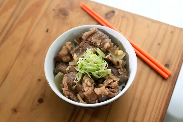 Foto wazig smakelijke homade japanse gyudon. beef bowl met lente-ui bovenop