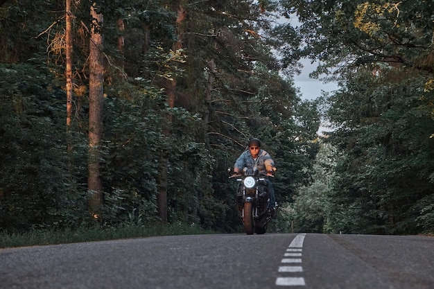 Wazige beweging een jonge man fietser in een helm rijdt snel met hoge snelheid op een bosweg in beweging