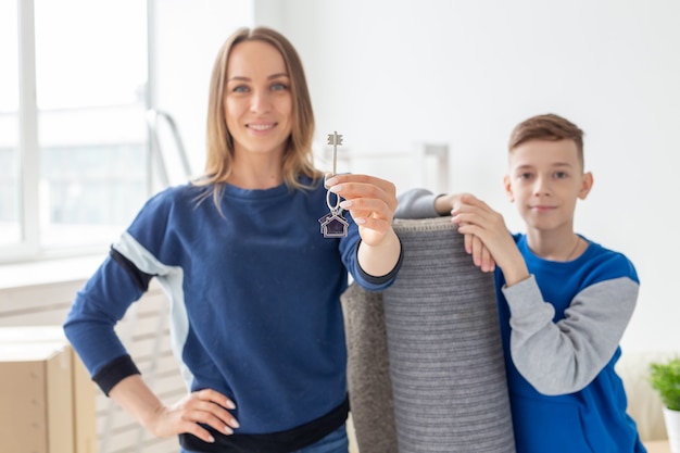 Wazige knappe moeder en zoon houden de sleutels van een nieuw appartement vast na de housewarming. Nieuw