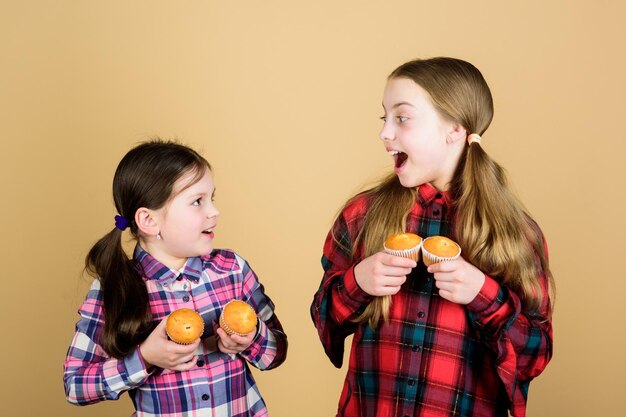 We all love desserts small children happy smiling with cupcake\
dessert in hands happy little girls enjoy eating dessert course\
cupcake is commonly found in dessert course