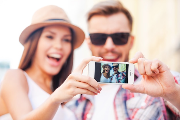 We are beautiful! Happy young loving couple making selfie while standing outdoors together