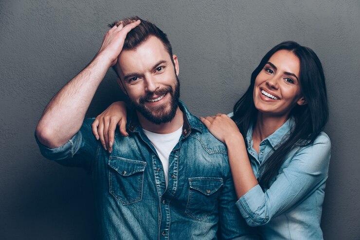 Photo we are better when we together. studio shot of beautiful young couple in jeans wear standing close to each other and looking at camera with smile