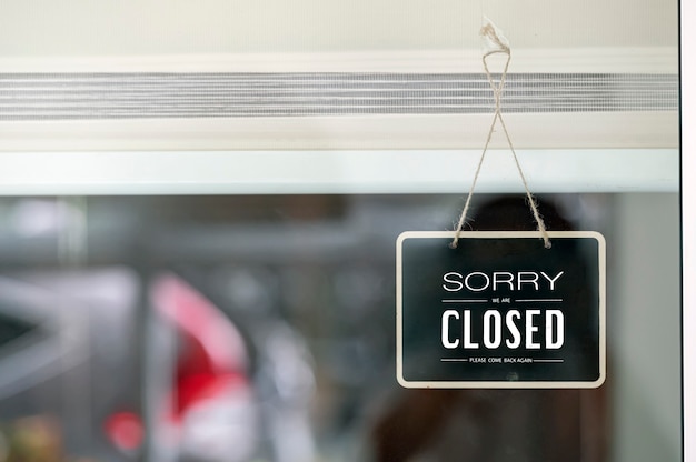 Photo we are closed sign board looking through the glass of store window.