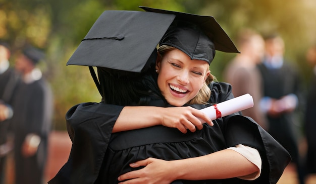 We are finally here Two college graduates hugging one another in congratulations