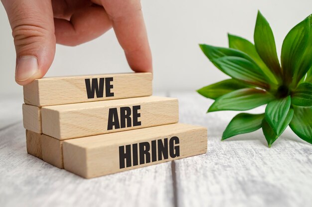 Photo we are hiring words on wooden block and businessman hand