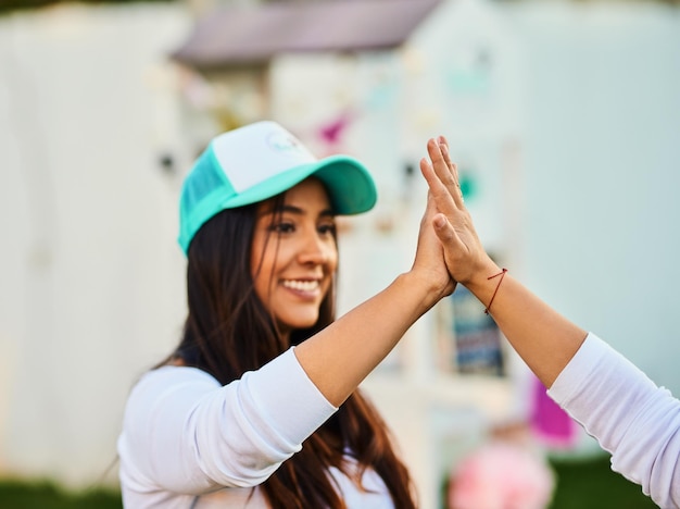 We are professionals Shot of a cheerful young woman giving another person a high five outside during the day