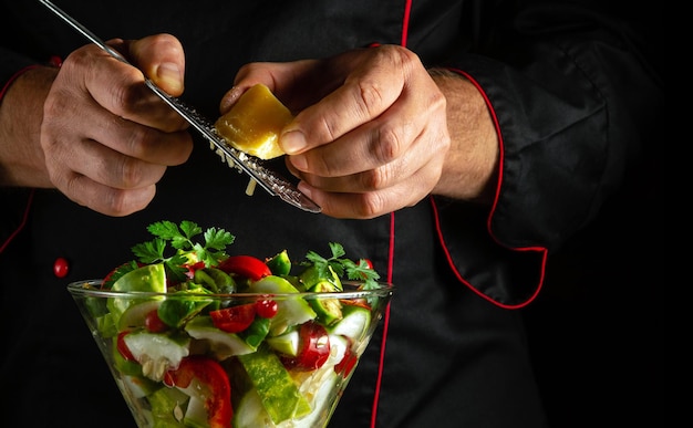 We bereiden een gezonde salade van verse groenten voor het diner de chef-kok voegt kaas toe aan een schaal groenten vegetarisch voedsel concept in de keuken van het hotel