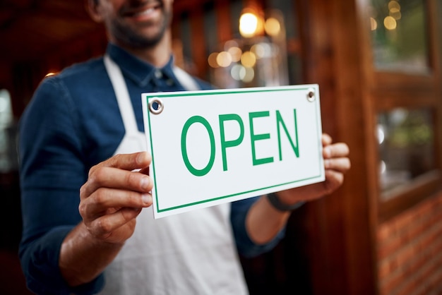 We can now safely say were open Shot of a unrecognizable business owner holding up a sign saying open while standing under a doorway at a beer brewery during the day