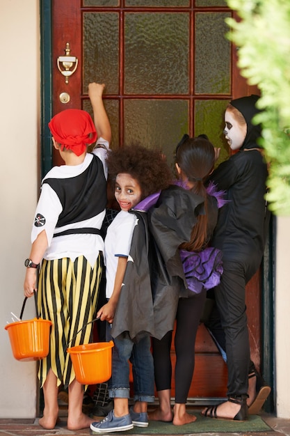 We cant wait for candy Rearview shot of some children knocking on a door during halloween