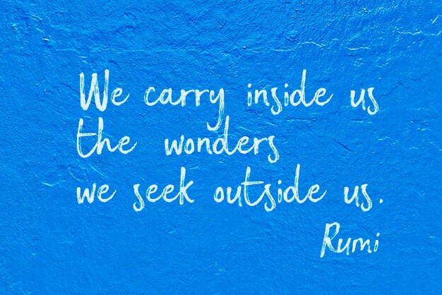 Photo we carry inside us the wonders we seek outside us - ancient persian poet and philosopher rumi quote handwritten on blue wall