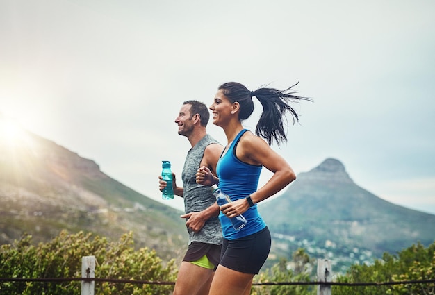 We compete in a friendly way shot of a young attractive couple training for a marathon outdoors