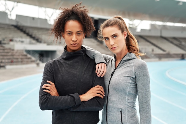 We dare you to try stop us Cropped portrait of two attractive young athletes standing together after a run on a track field during a training session