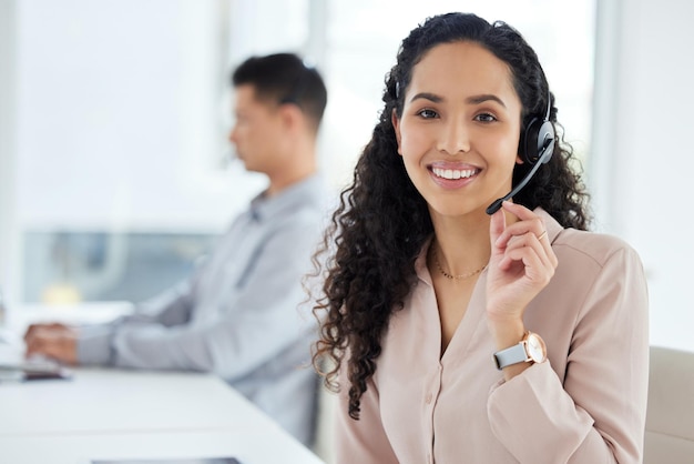 Foto offriamo un ottimo servizio ritratto di un giovane agente di call center che lavora in un ufficio con il suo collega in background