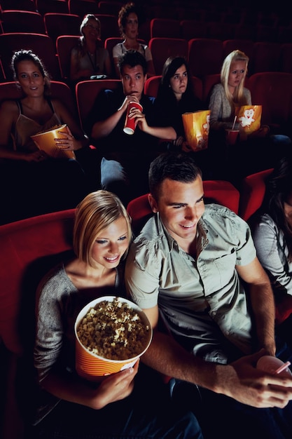 We found love at the movies A happy young couple watching a movie at the cinema together